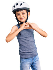 Little cute boy kid wearing bike helmet smiling in love showing heart symbol and shape with hands. romantic concept.
