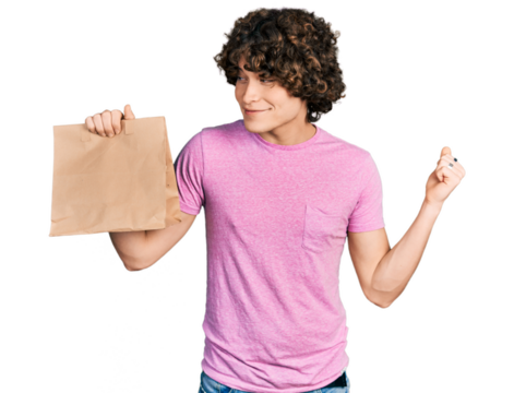 Caucasian teenager holding take away paper bag screaming proud, celebrating victory and success very excited with raised arm