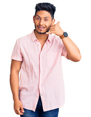 Handsome latin american young man wearing casual summer shirt smiling doing phone gesture with hand and fingers like talking on the telephone. communicating concepts.