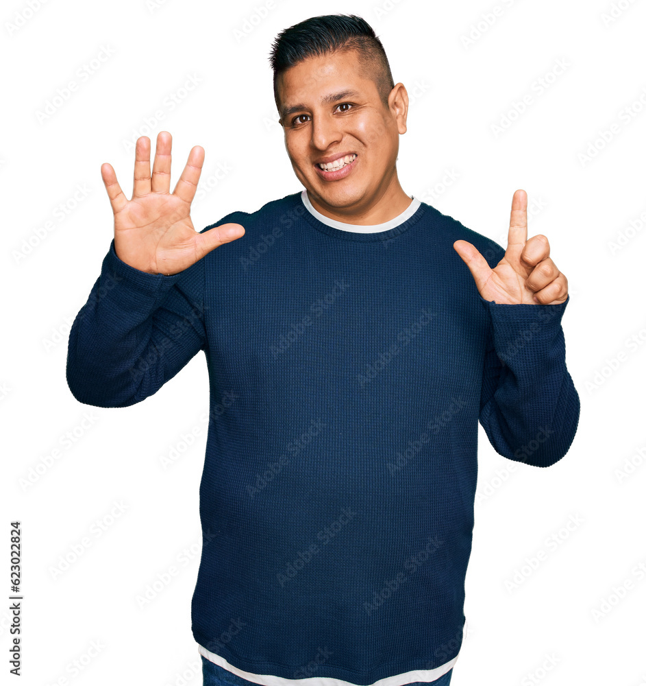 Poster Young latin man wearing casual clothes showing and pointing up with fingers number seven while smiling confident and happy.