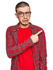 Hispanic young man wearing casual clothes pointing aside worried and nervous with forefinger,...