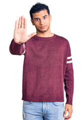 Hispanic handsome young man wearing casual clothes doing stop sing with palm of the hand. warning expression with negative and serious gesture on the face.