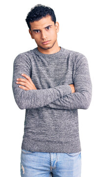 Hispanic handsome young man wearing casual sweater skeptic and nervous, disapproving expression on face with crossed arms. negative person.