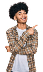 Young african american man with afro hair wearing casual clothes with a big smile on face, pointing with hand and finger to the side looking at the camera.