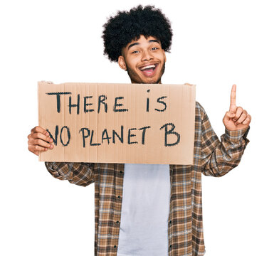 Young African American Man With Afro Hair Holding There Is No Planet B Banner Surprised With An Idea Or Question Pointing Finger With Happy Face, Number One