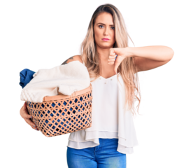 Young beautiful blonde woman holding laundry basket with angry face, negative sign showing dislike with thumbs down, rejection concept