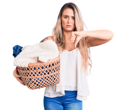Young beautiful blonde woman holding laundry basket with angry face, negative sign showing dislike with thumbs down, rejection concept