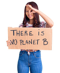Young beautiful chinese girl holding there is no planet b banner smiling happy doing ok sign with hand on eye looking through fingers