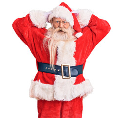 Old senior man with grey hair and long beard wearing traditional santa claus costume crazy and scared with hands on head, afraid and surprised of shock with open mouth