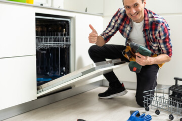 Repairman Repairing Dishwasher With Screwdriver In Kitchen 