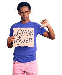 African handsome man holding woman power banner with angry face, negative sign showing dislike with thumbs down, rejection concept