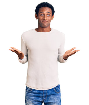 African handsome man wearing casual winter sweater clueless and confused expression with arms and hands raised. doubt concept.