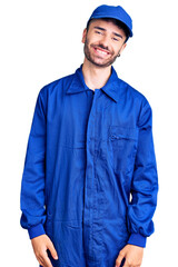 Young hispanic man wearing painter uniform looking positive and happy standing and smiling with a confident smile showing teeth
