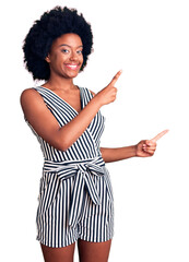 Young african american woman wearing casual clothes smiling and looking at the camera pointing with two hands and fingers to the side.