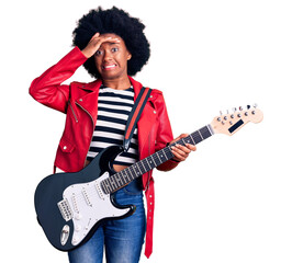 Obraz premium Young african american woman playing electric guitar stressed and frustrated with hand on head, surprised and angry face