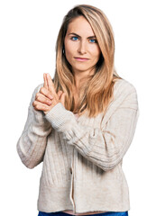 Obraz premium Young blonde woman wearing casual clothes holding symbolic gun with hand gesture, playing killing shooting weapons, angry face