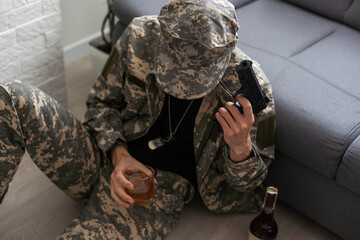 Unhappy man in camouflage uniform sitting at arm chair over white studio background, touching his...