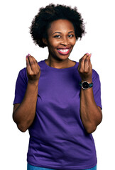 African american woman with afro hair wearing casual purple t shirt doing money gesture with hands, asking for salary payment, millionaire business