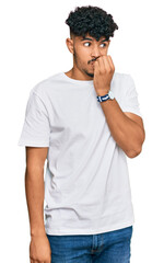 Young arab man wearing casual white t shirt looking stressed and nervous with hands on mouth biting nails. anxiety problem.