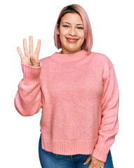 Hispanic woman with pink hair wearing casual winter sweater showing and pointing up with fingers number four while smiling confident and happy.