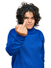 Young hispanic woman with curly hair wearing turtleneck sweater showing middle finger, impolite and...
