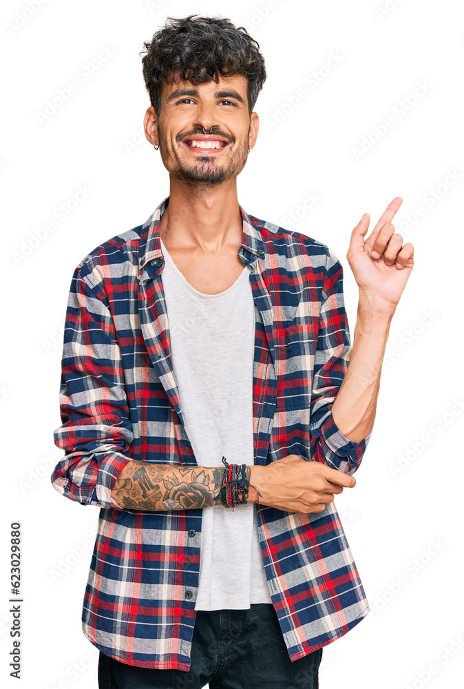 Sticker young hispanic man wearing casual clothes with a big smile on face, pointing with hand and finger to