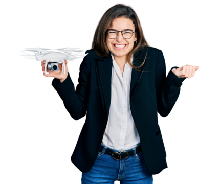 Young caucasian girl wearing business style holding drone screaming proud, celebrating victory and success very excited with raised arm