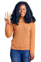 Beautiful african american woman wearing casual  sweater showing and pointing up with fingers number three while smiling confident and happy.