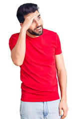 Young handsome man with beard wearing casual t-shirt very happy and smiling looking far away with hand over head. searching concept.