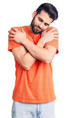 Young handsome man with beard wearing casual t-shirt hugging oneself happy and positive, smiling confident. self love and self care