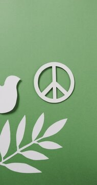 Vertical video of white dove with peace sign and leaf and copy space on green background