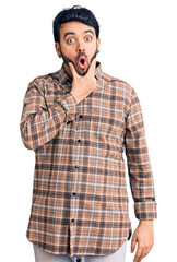 Young hispanic man wearing casual clothes looking fascinated with disbelief, surprise and amazed expression with hands on chin