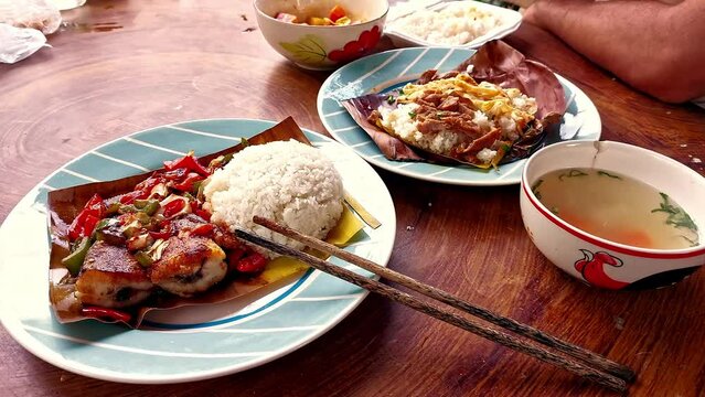Eating authentic traditional khmer food for breakfast of Trei boeng kanh chhet or spicy fried fish and Bai sach chrouk or pork with steamed rice