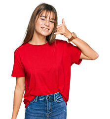 Teenager caucasian girl wearing casual red t shirt smiling doing phone gesture with hand and fingers like talking on the telephone. communicating concepts.