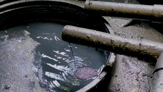 Black chemical wastewater coming out from pipe to storage tank from industrial processes. Hazardous and toxic waste - WWTP Wastewater Treatment Procedure