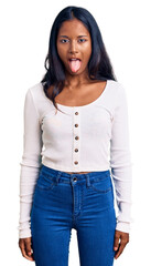 Young indian girl wearing casual clothes sticking tongue out happy with funny expression. emotion concept.