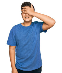 Teenager hispanic boy wearing casual clothes smiling and laughing with hand on face covering eyes for surprise. blind concept.