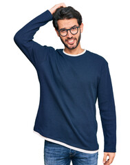 Young hispanic man wearing casual clothes and glasses confuse and wonder about question. uncertain...