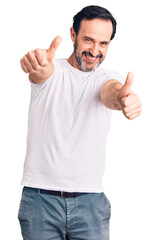 Middle age handsome man wearing casual t-shirt approving doing positive gesture with hand, thumbs up smiling and happy for success. winner gesture.