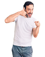 Fototapeta premium Middle age handsome man wearing casual t-shirt smiling doing talking on the telephone gesture and pointing to you. call me.