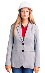 Beautiful young woman wearing architect hardhat relaxed with serious expression on face. simple and natural looking at the camera.