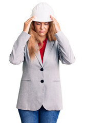 Beautiful young woman wearing architect hardhat with hand on head for pain in head because stress. suffering migraine.