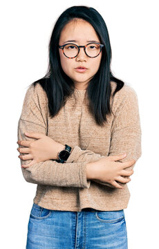Young chinese woman wearing casual sweater and glasses shaking and freezing for winter cold with sad and shock expression on face