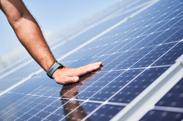 Engineer checking an operation of just installed solar battery. Close up view of hand on PV panel....