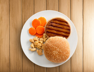 Hamburguesa vegana de pollo con zanahoria sobre mesa de madera, vista cenital. Vegan chicken burger with carrot on wooden table, top view.