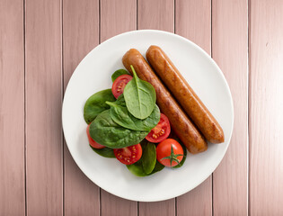 Salchichas de pollo con ensalada de espinacas y tomates cherries vista cenital. Chicken sausages with spinach salad and cherry tomatoes overhead view.