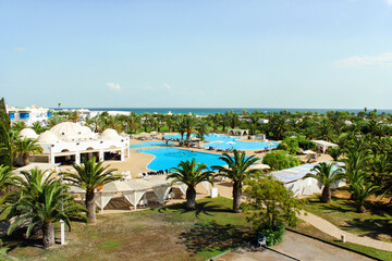 Top view of the hotel complex on the first coastal line of the sea. Beautiful green area with pool and places for relaxation. The concept of tourism, vacations, and recreation