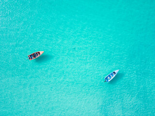 Aerial top view of two empty fishing boats moored on shallows in turquoise transparent Caribbean sea water. Minimalistic copy space tropical background