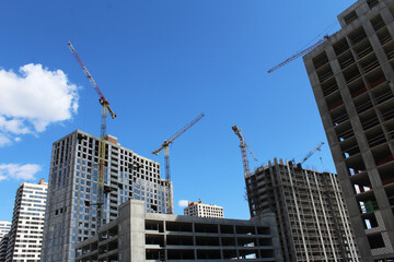 Fototapeta na wymiar crane on a background of blue sky. construction of a crane and a crane on a background of multi - storey buildings.