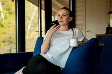 A woman with a phone in her hands speaks on a speakerphone, using a virtual digital voice...